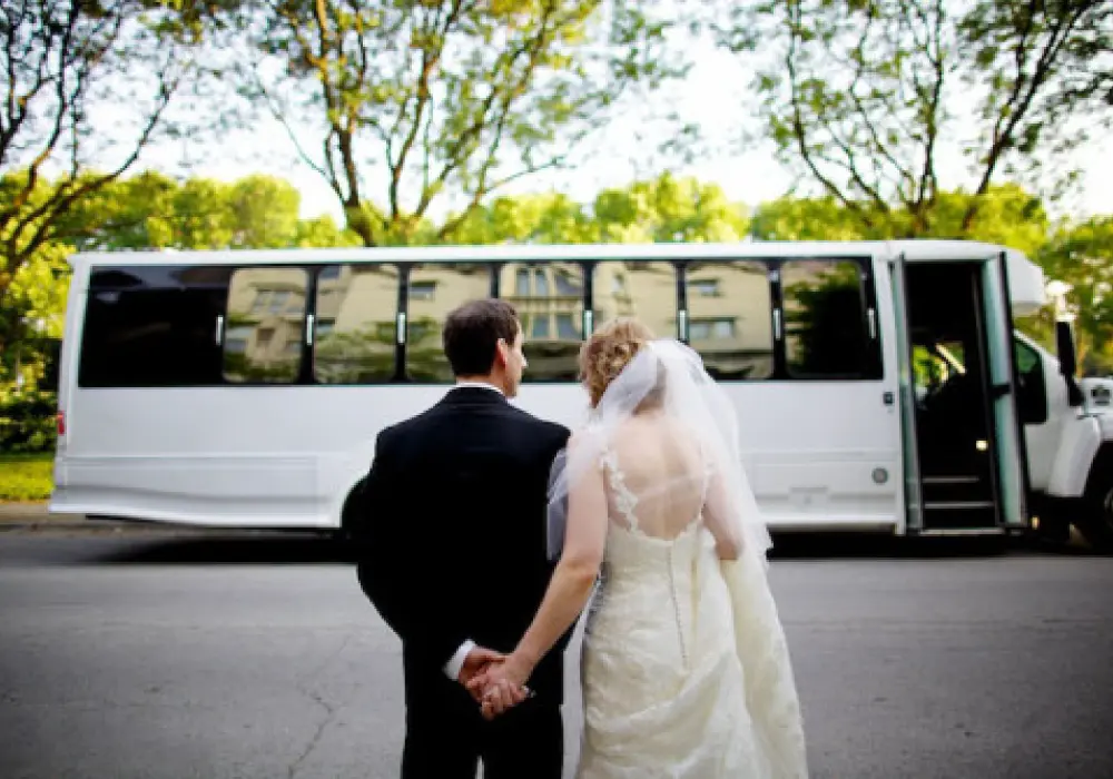 a bride and groom holding hands and standing next to a bus