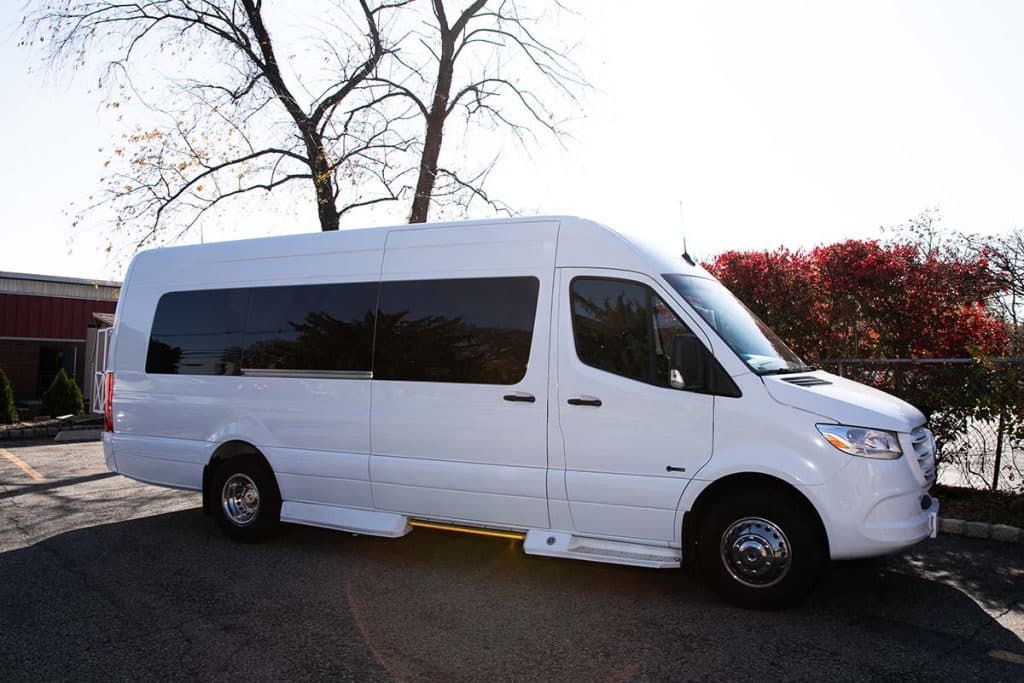 White 14 passenger Mercedes-Benz Sprinter van parked outside at dusk