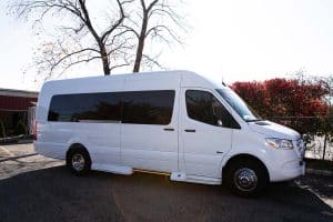 White 14 passenger Mercedes-Benz Sprinter van parked outside at dusk