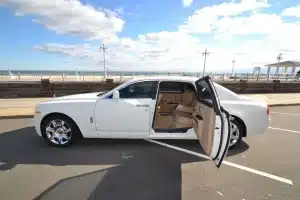 White Rolls-Royce Ghost parked on the boardwalk with its rear-hinged coach door open