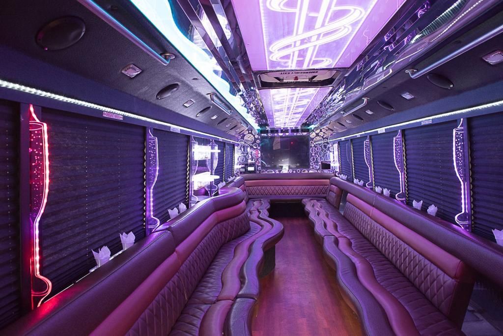 Party bus interior with purple LED lighting and quilted leather bench seating