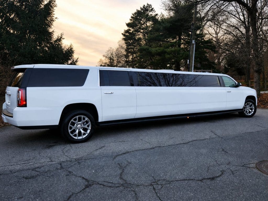 White 18 passenger stretch SUV limousine parked at sunset