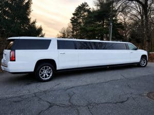 White 18 passenger stretch SUV limousine parked at sunset