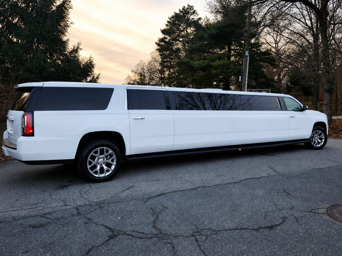White 18 passenger stretch SUV limousine parked at sunset