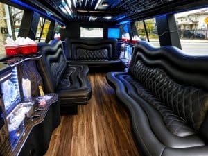 Stretch SUV limo interior with fiber-optic star ceiling, lit bar, and black diamond-stitched leather seating