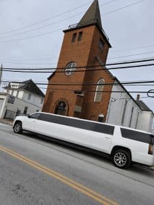 Side view of the white 18 passenger stretch SUV limo on a city street