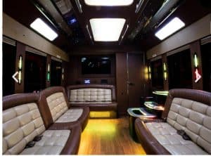 Interior of the 35 passenger party bus showing the onboard restroom door, bar table and wraparound leather seating